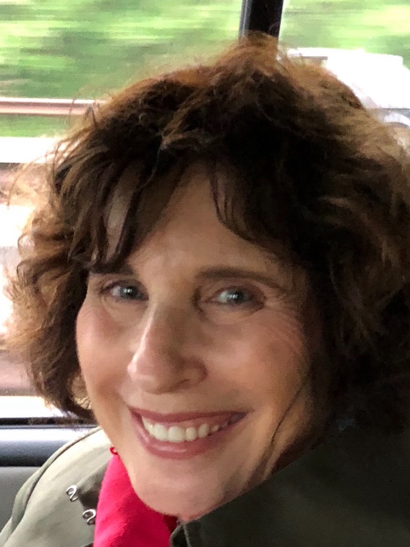 Susan Mailer, smiling, photographed in a car window seat